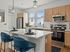 Modern kitchen with sleek white countertops, stainless steel appliances, and cozy seating at the island, exuding a welcoming and elegant ambiance.