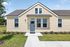 Charming single-story yellow house with a welcoming blue door and lush green lawn, perfect for family living.