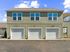 Charming two-story building with three stylish garage doors, perfect for convenient urban living.
