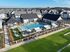 Vibrant community pool area with stylish sun lounges, cozy hammocks, and a well-maintained landscape, surrounded by modern houses under a clear blue sky.