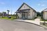 Charming modern cottage with inviting porch and manicured landscaping, ideal for cozy living in a serene neighborhood.