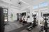 Modern apartment gym with state-of-the-art cardio machines and natural lighting, offering a refreshing workout experience.