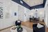 Contemporary apartment lobby with elegant decor, featuring stylish blue armchairs, a modern chandelier, and chic wall accents. Natural light enhances the sophisticated ambiance.
