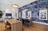 Modern open-concept lounge with vibrant blue botanical wallpaper, stylish wood furniture, and elegant hanging lights.