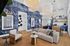 Chic modern living space featuring a cozy sofa, stylish wicker chair, and vibrant blue accent wall with nature-inspired art.