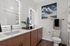 Modern bathroom featuring sleek dual vanity with illuminated mirrors, elegant wood cabinetry, and stylish decor accents.