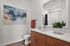 Contemporary bathroom with elegant wooden cabinetry, abstract wall art, and vibrant green potted plant enhancing the space.