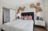 Inviting bedroom featuring stylish woven wall decor, modern bedside tables, and cozy bedding with colorful accent pillows.