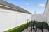 Charming outdoor patio with elegant white fencing, featuring cozy seating and lush artificial grass.