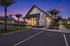Charming leasing office at sunset with warm lighting, surrounded by palm trees and inviting seating area.