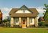 Delightful single-story house with a stone facade, inviting front porch, and lush green lawn.