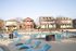 Inviting community pool area with stylish lounge chairs and charming houses in the background.