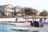 Charming community pool area featuring comfortable lounge chairs, pergola, and scenic townhouses.