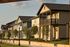 Row of charming suburban homes with front porches and landscaped gardens, bathed in warm sunlight.