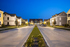 Charming neighborhood street lined with elegant houses at dusk, illuminated by street lamps.