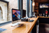 Modern commercial workspace with wood counter, computers, large windows, and a TV screen.