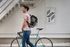Man with a backpack walking beside a bicycle in a modern urban setting.