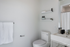 Modern bathroom with sleek white fixtures, elegant shelving, and minimalist design.