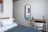 Bright, modern bedroom featuring a cozy desk space and chic wall mirror, ideal for urban living.