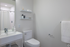Modern and minimalistic bathroom featuring sleek fixtures, elegant shelving, and a pristine shower area.