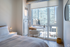 Sunlit bedroom with a cozy desk overlooking a stunning cityscape, perfect for urban living.