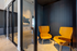 Chic modern office space with vibrant orange chairs and sleek glass partitions, exuding a stylish and welcoming ambiance.