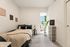 Cozy, light-filled bedroom with a stylish bed, decorative artwork, and a modern chest of drawers, creating an inviting ambiance.