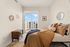 Bright and cozy bedroom with modern decor, large window offering urban views, and elegant earth-toned bedding.