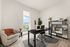 Elegant home office with modern decor, featuring a sleek black desk, cozy armchair, and large window with a stunning city view.
