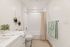 Chic and serene bathroom with a modern bathtub, plush towels, and stylish decor including hanging plants for a fresh touch.
