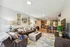 Inviting open-concept living area with stylish decor, featuring a cozy leather sofa, modern kitchen with stainless steel appliances, and a vibrant geometric rug.