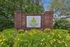 Charming entrance to The View apartments with vibrant yellow flowers and lush greenery.