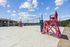 Inviting outdoor sand volleyball court with vibrant pink chairs and clear blue sky, providing a perfect space for active recreation and relaxation.