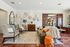 Elegant living room with cozy seating, decorative wall art, and a vintage chest, showcasing warm earth tones and stylish decor.