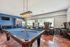 Chic recreational space featuring a stylish pool table, modern lighting, and cozy seating areas perfect for relaxation.