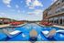 Luxurious outdoor pool area with stylish sun loungers and water features, set against a backdrop of clear blue skies and modern architecture.