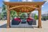 Beautiful outdoor gazebo with cozy red-cushioned wicker seating, set against a backdrop of lush greenery and residential buildings.