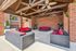 Charming outdoor lounge with vibrant red seating under a wooden pergola, perfect for relaxation and entertaining.