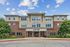 Modern apartment building with elegant brick and stucco design at 'The View,' surrounded by lush greenery and blue skies.