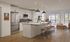 Modern open-concept kitchen and living area with sleek appliances and large windows, offering ample natural light and a stylish ambiance.