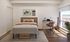 Bright and modern bedroom with a chic bed, stylish artwork, sleek desk setup, and scenic city view.