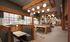 Chic, well-lit dining area with modern wooden decor, cozy booth seating, and stylish hanging light fixtures, perfect for relaxation.