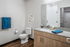Modern bathroom featuring sleek granite countertop, elegant wooden cabinetry, and stylish decor with fresh plant artwork.