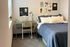 Cozy bedroom with stylish decor, featuring a comfortable bed, a modern desk, and vibrant wall art creating an inviting atmosphere.
