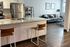 Modern open-concept kitchen and living area with granite counters, stylish bar stools, and a cozy gray sofa, perfect for comfortable living and entertaining.