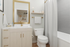 Elegant bathroom interior featuring a modern vanity with a gold-framed mirror, polished fixtures, and a cozy shower area with soft lighting.