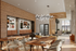 Modern and inviting lounge area featuring sleek wooden tables, cozy seating, and stylish wall art, illuminated by a contemporary chandelier.
