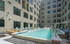 Modern apartment complex featuring a luxurious outdoor swimming pool surrounded by stylish lounge chairs, perfect for relaxation and enjoyment.