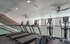 Modern fitness center with sleek treadmills and ellipticals, featuring a stylish geometric accent wall and abundant natural light.