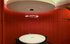Elegant circular meeting room with modern pendant lighting and vibrant red acoustic walls.
